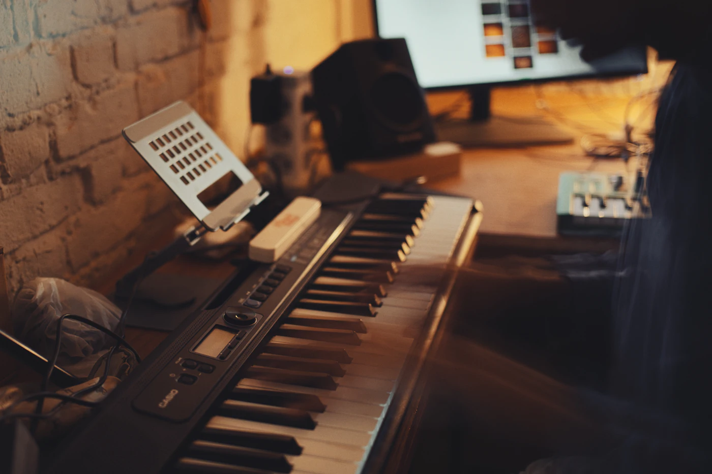 Keyboard, laptop and monitors on a desk against a brick wall
